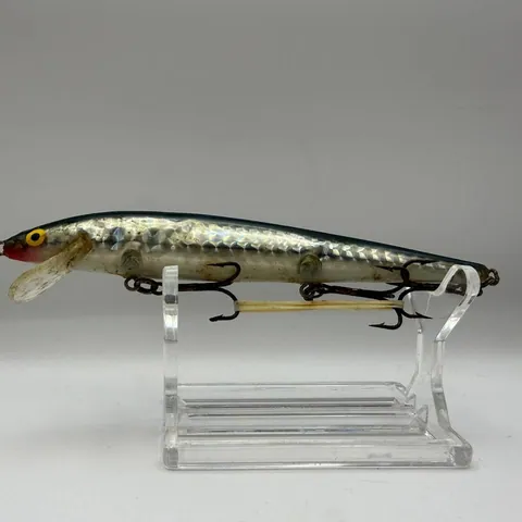 Wobler minnow o ciemnym grzbiecie i srebrnych bokach na stojaku